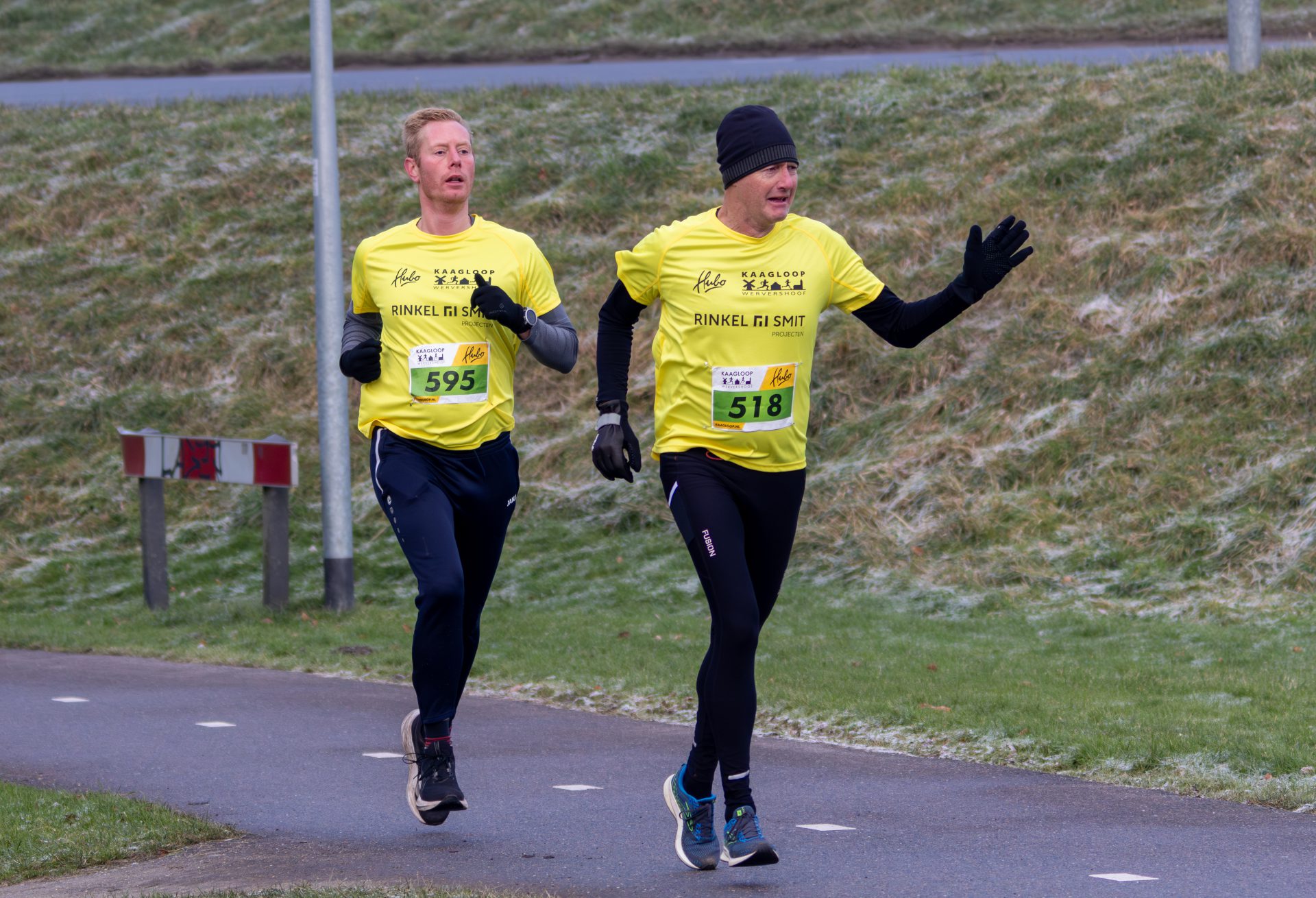 Lopers van de Kaagloop op de dijk langs het Kagerbos, met op de achtergrond een windmolen